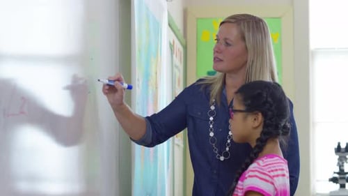 Student goes to front of class and writes on board in school classroom