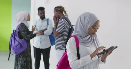 Muslim-Student mit Gruppe von Freunden im Hintergrund in traditioneller islamischer Hijab-Kleidung und