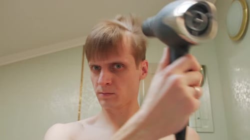 Man Styling Hair With Hairdryer and Comb