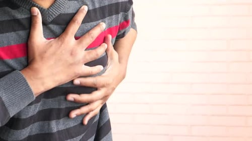 Young Man Suffering Pain in Heart and Holding Chest with Hand