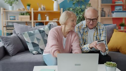 Senior Husband and Wife Making Electronic Payment with Bank Card and Laptop
