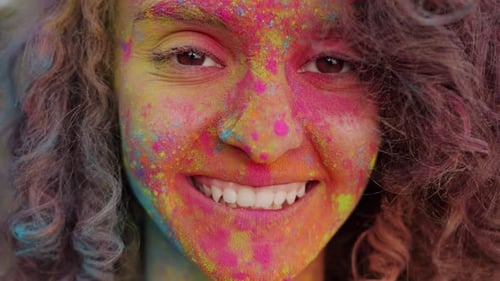Closeup Portrait of Cheerful Mixed Race Girl Dirty with Bright Gulal Paint Smiling Outdoors