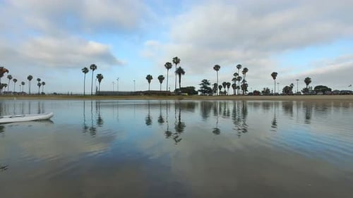 Tracking view of a man paddling his SUP stand-up paddleboard in a lake