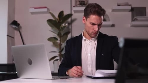 Man Employer Looking at Resume and Working with Laptop Sitting at Table in Office Spbi