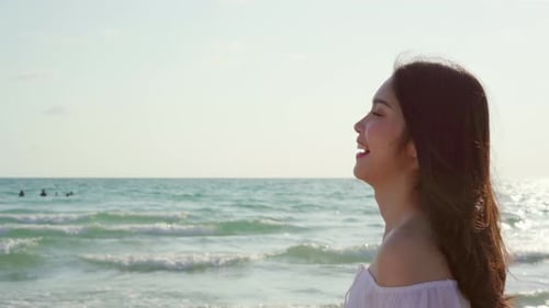 Beautiful female happy relax walking on beach near sea when sunset in evening.