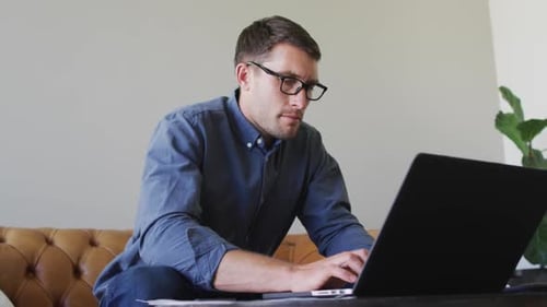 Caucasian man with glasses working from home using laptop
