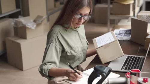 Woman Working at Desk Scanning Package in Warehouse