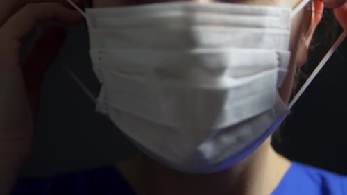 Woman Puts On a Surgical Mask Close Up