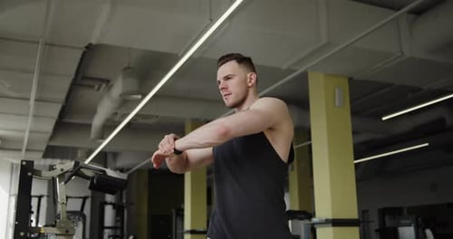 Young Muscular Athlete Works Out in a Modern Gym Making Warmup Exercises