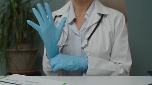 Doctor Puts on Blue Medical Gloves in Office