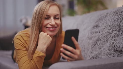 Mujer acostada en el sofá con el móvil