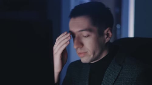 Depressed Male Businessman Man Works at a Laptop Computer Late at Night Suffers From Fatigue and