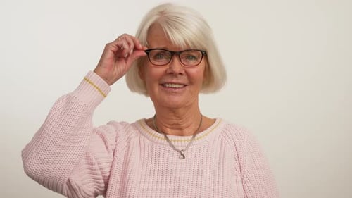 Smiling Senior Woman Adjusts Her Glasses Indoors