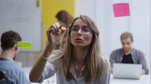 Woman Writing on Glass During a Business Meeting