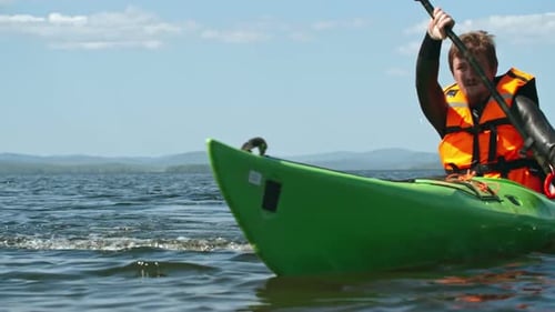 Man Paddles Kayak on Lake During Daytime