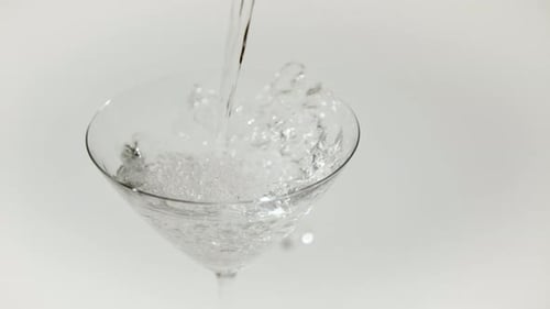 Clear Liquid Pouring into Martini Glass Overflowing