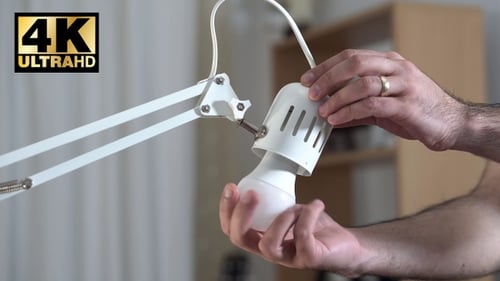Mann ersetzt alte Glühlampe durch neue LED-Lampe