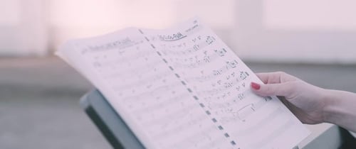 Hand Turns Pages of Sheet Music at Piano