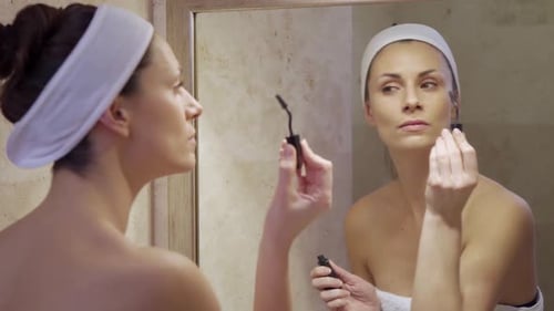 Beautiful Young Woman Paints Eyelashes in Mirror in Bathroom