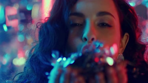 Gorgeous Girl Having Fun at Party. Woman Blowing Up Confetti in Nightclub