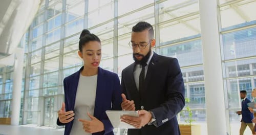 Mixed-race business people discussing over digital tablet in the lobby at office 4k