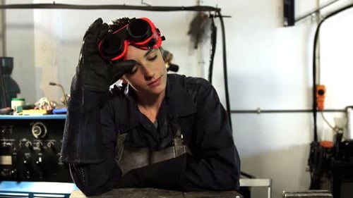 Female welder leaning in workshop