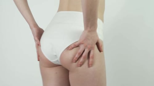 Young Woman Lift Her Buttocks with Her Hands on a White Background