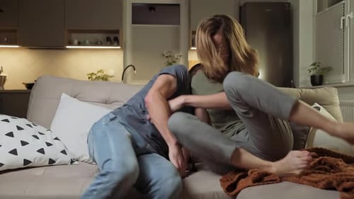 Couple Playfully Fighting for TV Remote on Couch