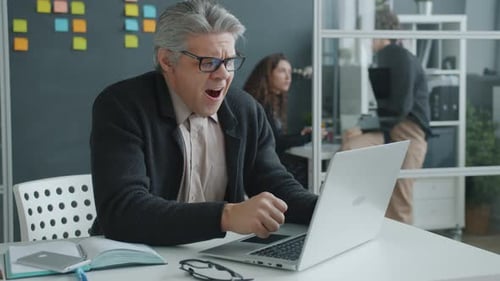 Frustrated Man Working on Laptop in Office