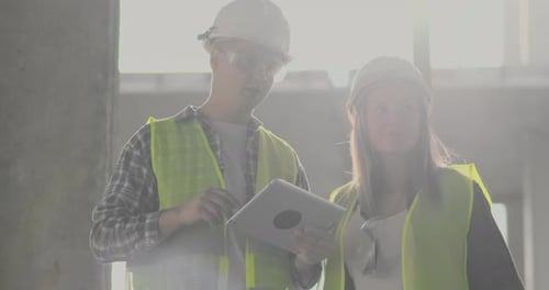 Un ouvrier de la construction et une femme architecte dans un casque discutent du plan de construction de la maison