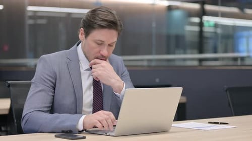 Geschäftsmann mittleren Alters mit Laptop beim Nickerchen im Büro