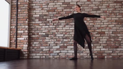 Graceful Woman Dances Elegantly in Studio by Brick Wall