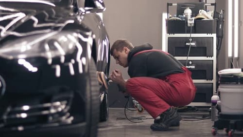 Man Polishing Black Car in Garage
