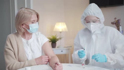 Eine Ärztin bereitet sich auf die Impfung einer Patientin vor