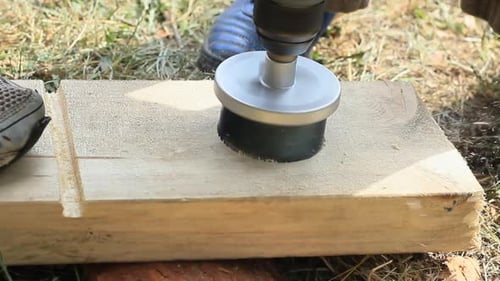 Person is Drilling a Hole in a Wooden Plank With Electrical Jigsaw