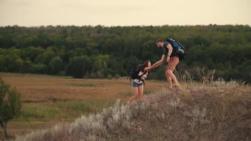 A Man Helps a Woman To Climb