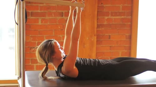 Woman Does Pilates on Reformer Machine