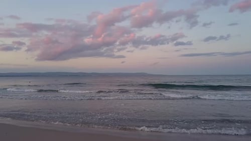 Aerial View of a Sea Surface with Blue Water Waves Under Purple Sunset Sky