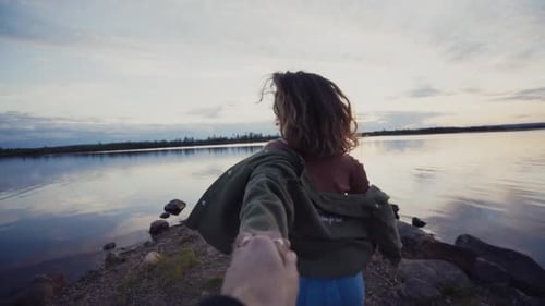 Cheerful woman holding hand with crop man on shore