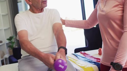 Video of happy biracial female physiotherapist exercising with caucasian senior man