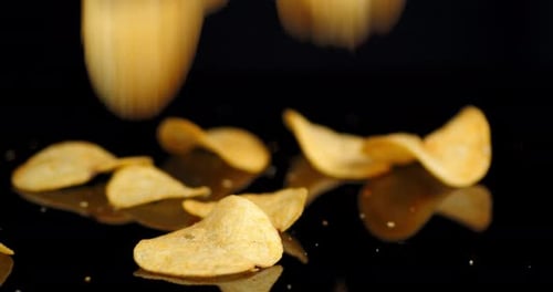 Crispy Potato Chips Falling onto Black Surface