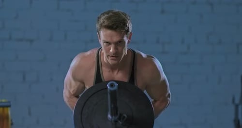Muscular Male Athlete Doing Exercises with a Barbell in the Gym Inflated Muscles of the Back and