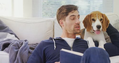 Man Reading with Beagle on Couch Indoors