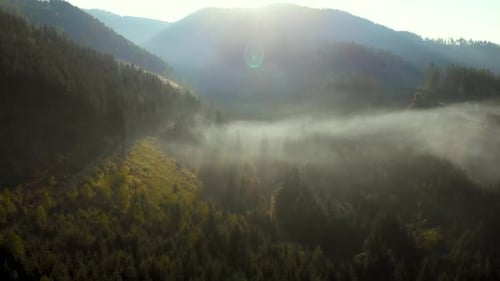 Aerial view of sunrise over foggy village in mountains.