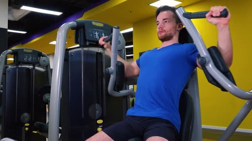 A Young Fit Man Trains on a Machine in a Gym - Closeup