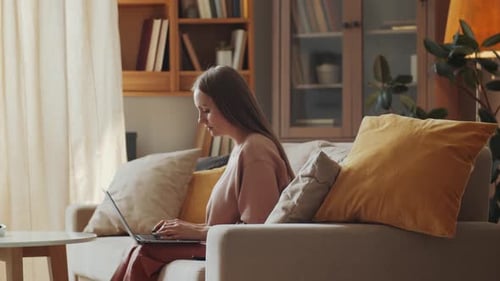 Woman Works on Laptop on Couch at Home