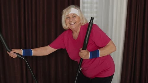 Senior Woman Exercises on Elliptical Machine at Home