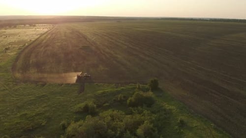 Aerial View of Farming Tractor Spraying on Field with Sprayer, Herbicides and Pesticides at Sunset