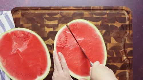 Schritt für Schritt. Ansicht von oben. Rote Wassermelone auf einem Holzschneidebrett schneiden.