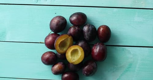 Pile of Ripe Plums on Blue Wood
